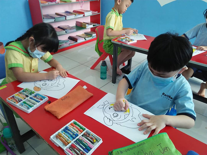 Rainbow Kids’ students colouring their masks before cutting them out